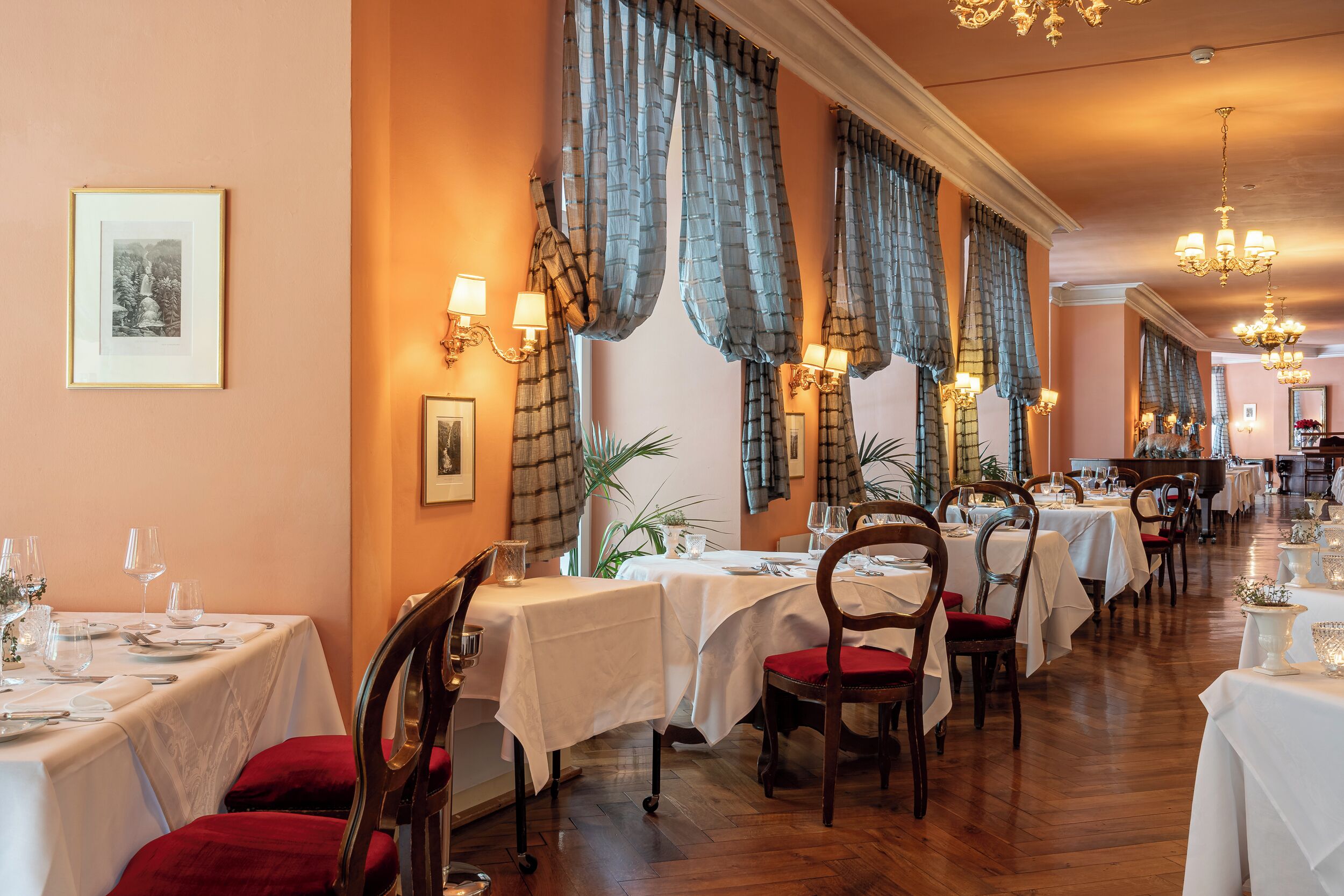 A restaurant with multiple tables, chairs, and a piano.