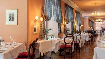 A restaurant with multiple tables, chairs, and a piano.
