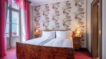 Ein Schlafzimmer mit einem hölzernen Bett, floralem Wandpapier und zwei Nachttischlampen.