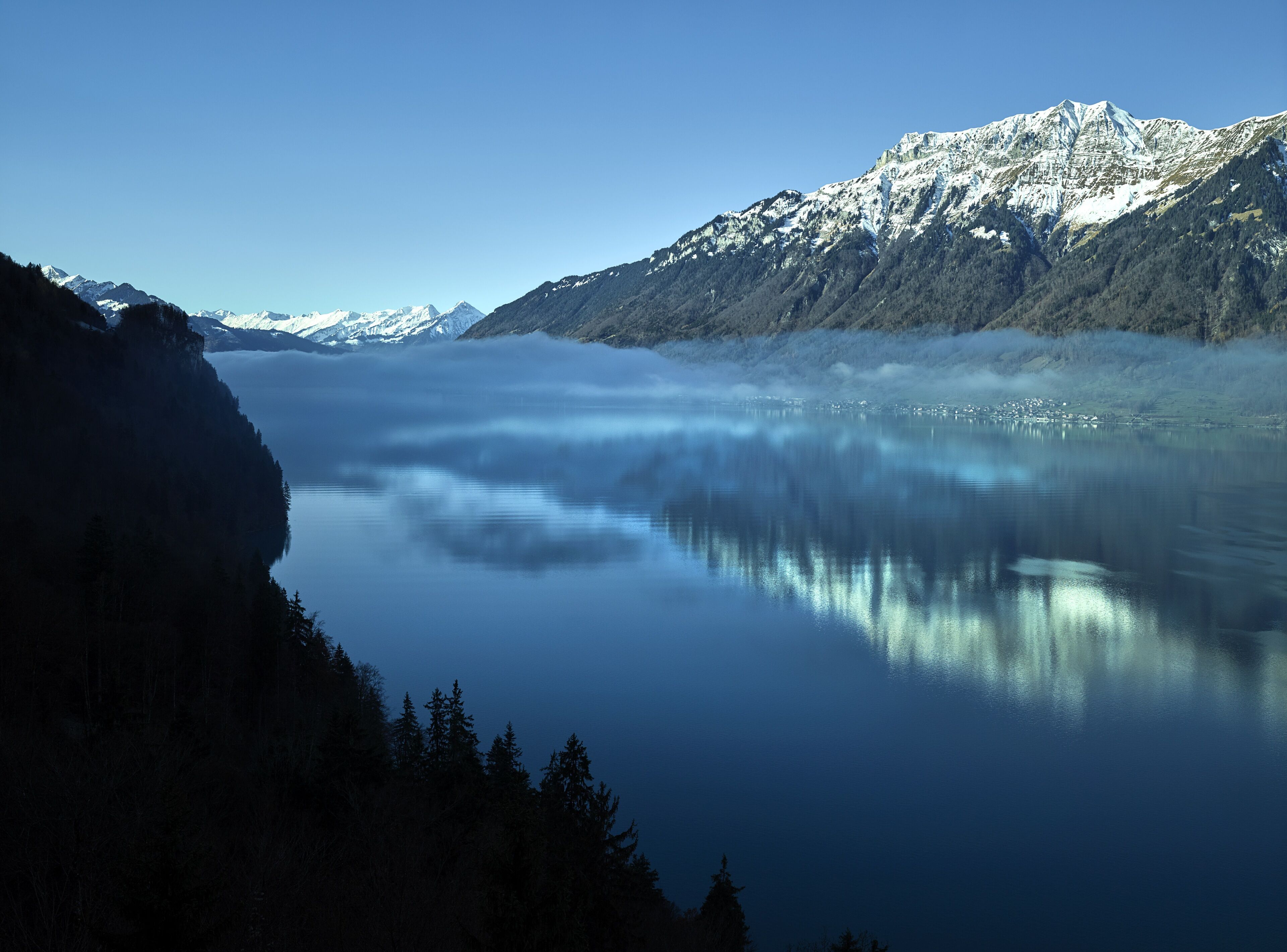 Un lac paisible, entouré de montagnes enneigées et de forêts denses.