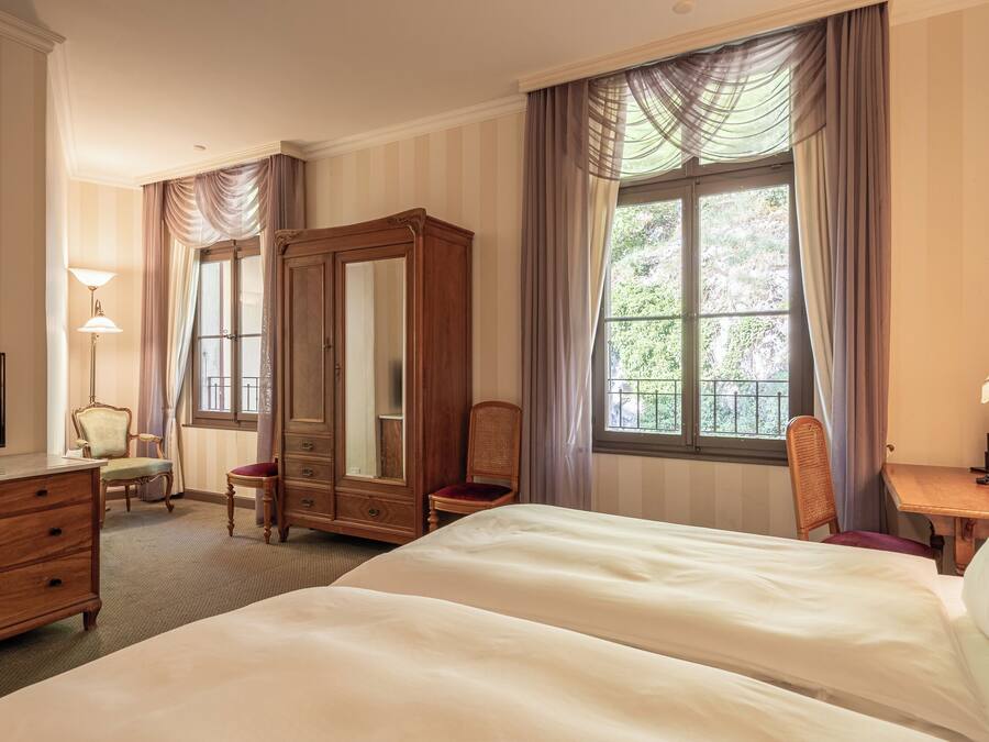 Habitación de hotel con una cama grande, un armario, un escritorio con lámpara, una silla y un televisor.