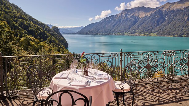 Une table dressée pour le dîner, avec vue sur un lac et des montagnes.