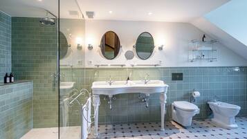 Une salle de bain moderne dotée d’une douche à parois de verre, de deux lavabos, de toilettes et d’un bidet.