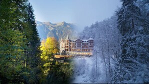 Un hôtel au style architectural traditionnel, entouré d’arbres couverts de neige et avec des montagnes enneigées en toile de fond.
