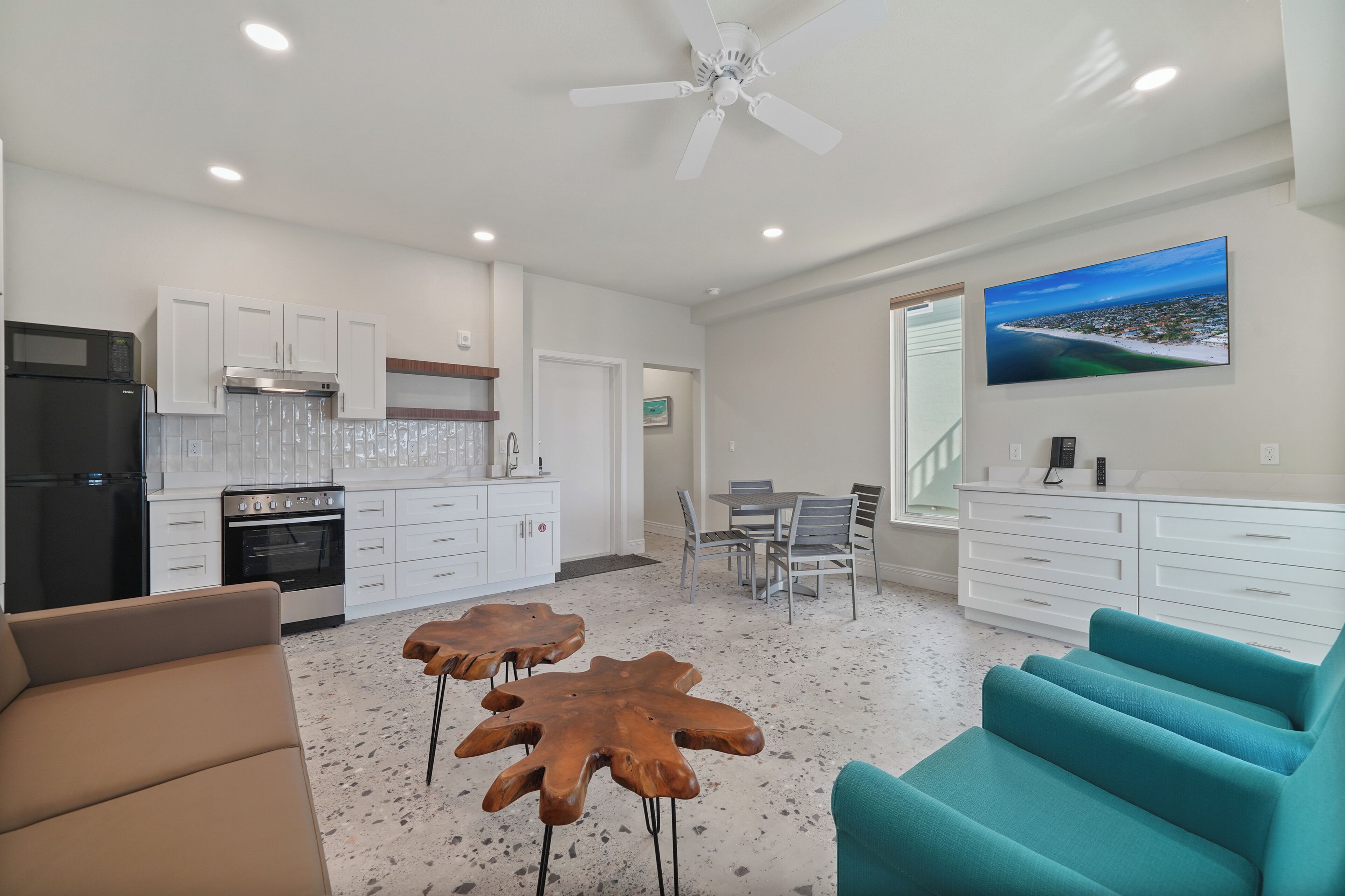 A modern kitchen with white cabinets, a black refrigerator, and a dining area with a table and chairs.
