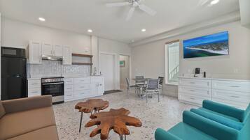 A modern kitchen with white cabinets, a black refrigerator, and a dining area with a table and chairs.