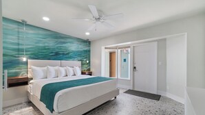 Una camera da letto moderna con un letto, una ventola a soffitto, un affresco sulla parete e una porta con il segnale di uscita.