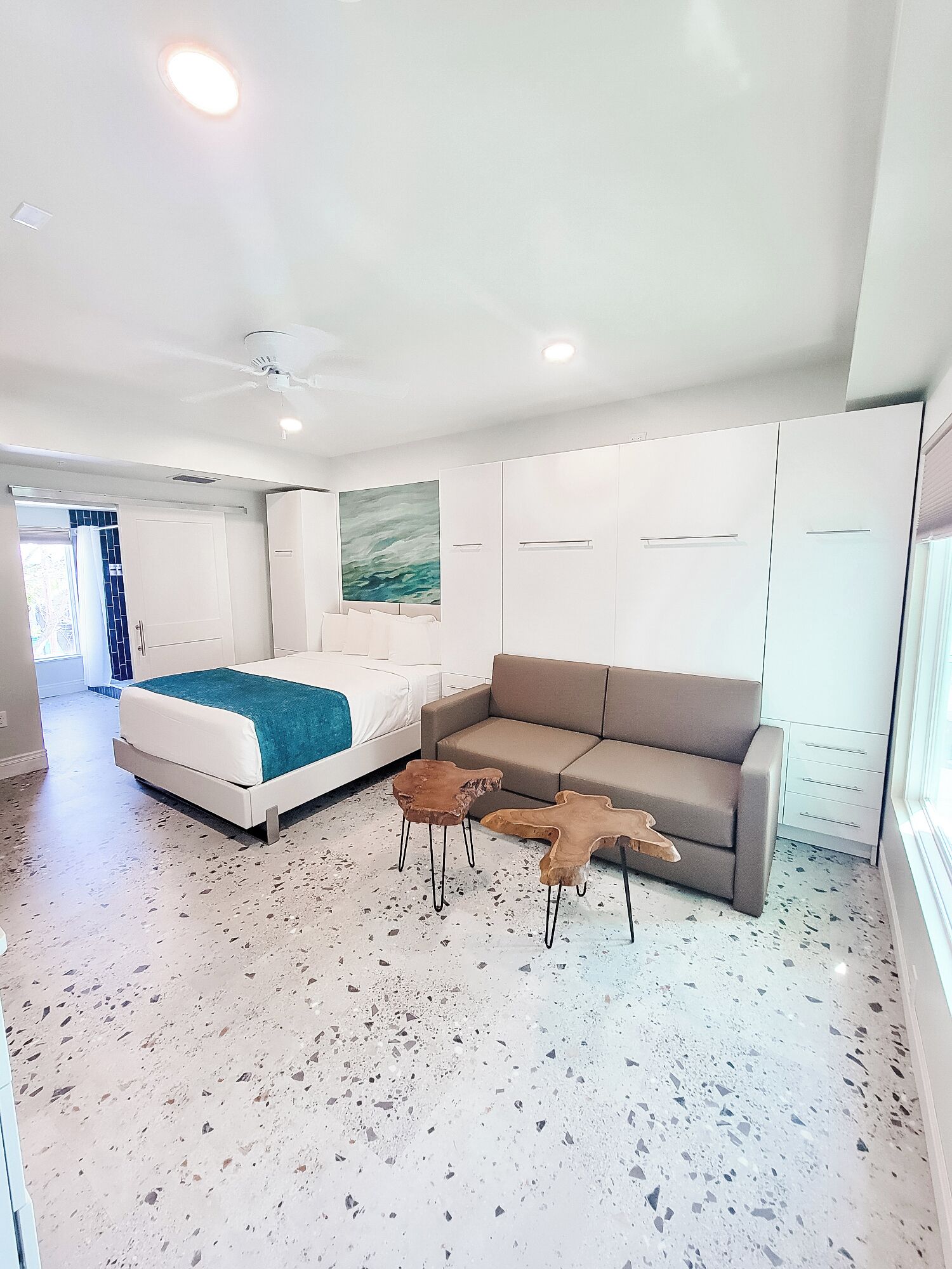A modern bedroom with a bed, a sofa, and two wooden coffee tables.