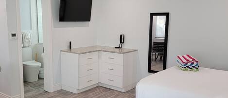 Une chambre d’hôtel moderne équipée d’un lit, d’un téléviseur fixé au mur, d’une table de chevet, d’une commode et d’un miroir.