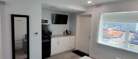 Una sala de estar moderna con un sofá blanco, una mesa de centro blanca y un ventanal con persianas.