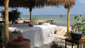 A beachside room with a thatched roof, a bed, and a view of the sea. - Silver Surf Gulf Beach Resort (Bradenton Beach)