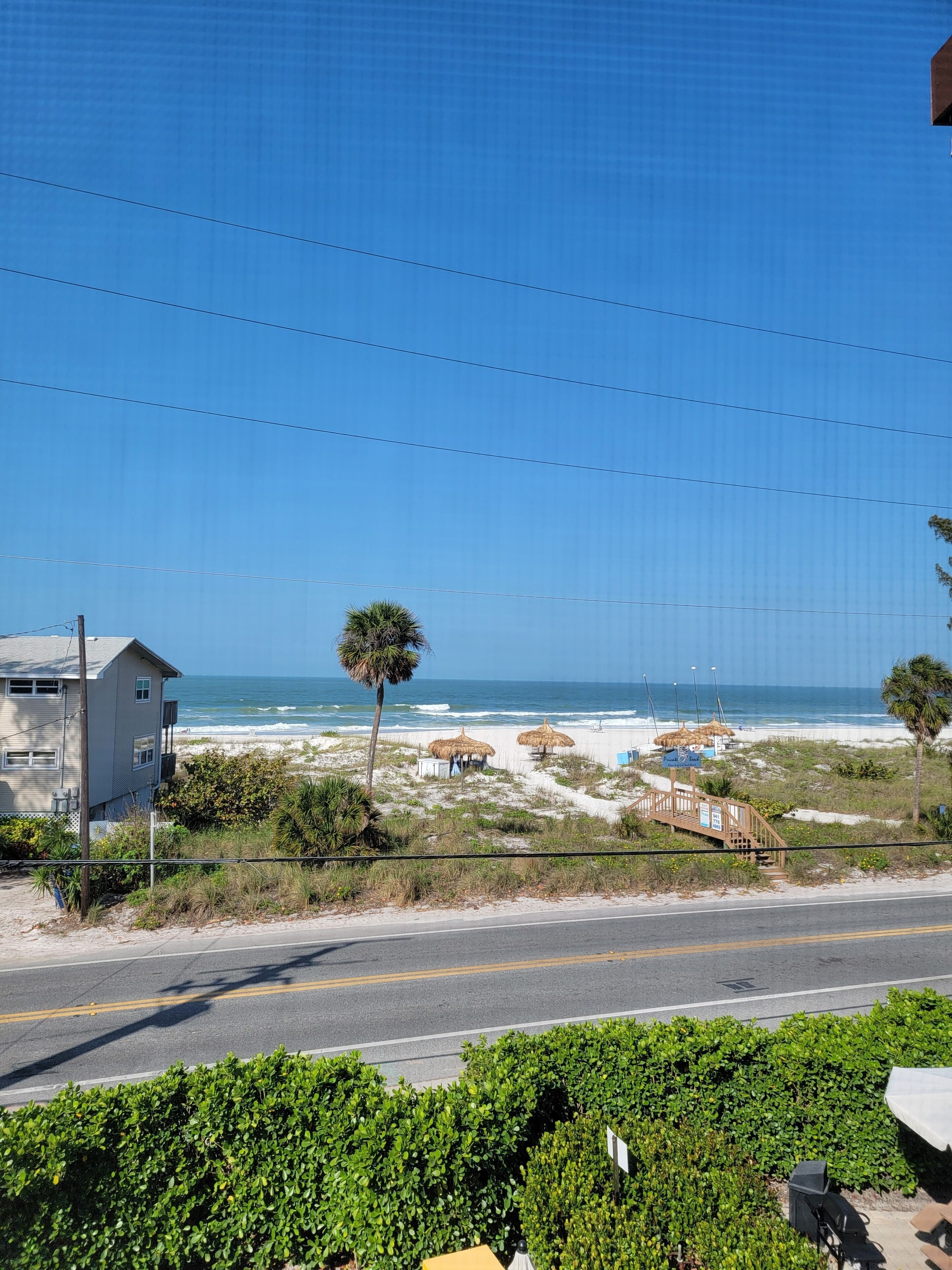 A coastal road with a beach and a building.