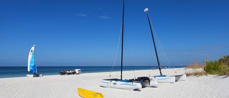 A beach with several boats and a yellow kayak.