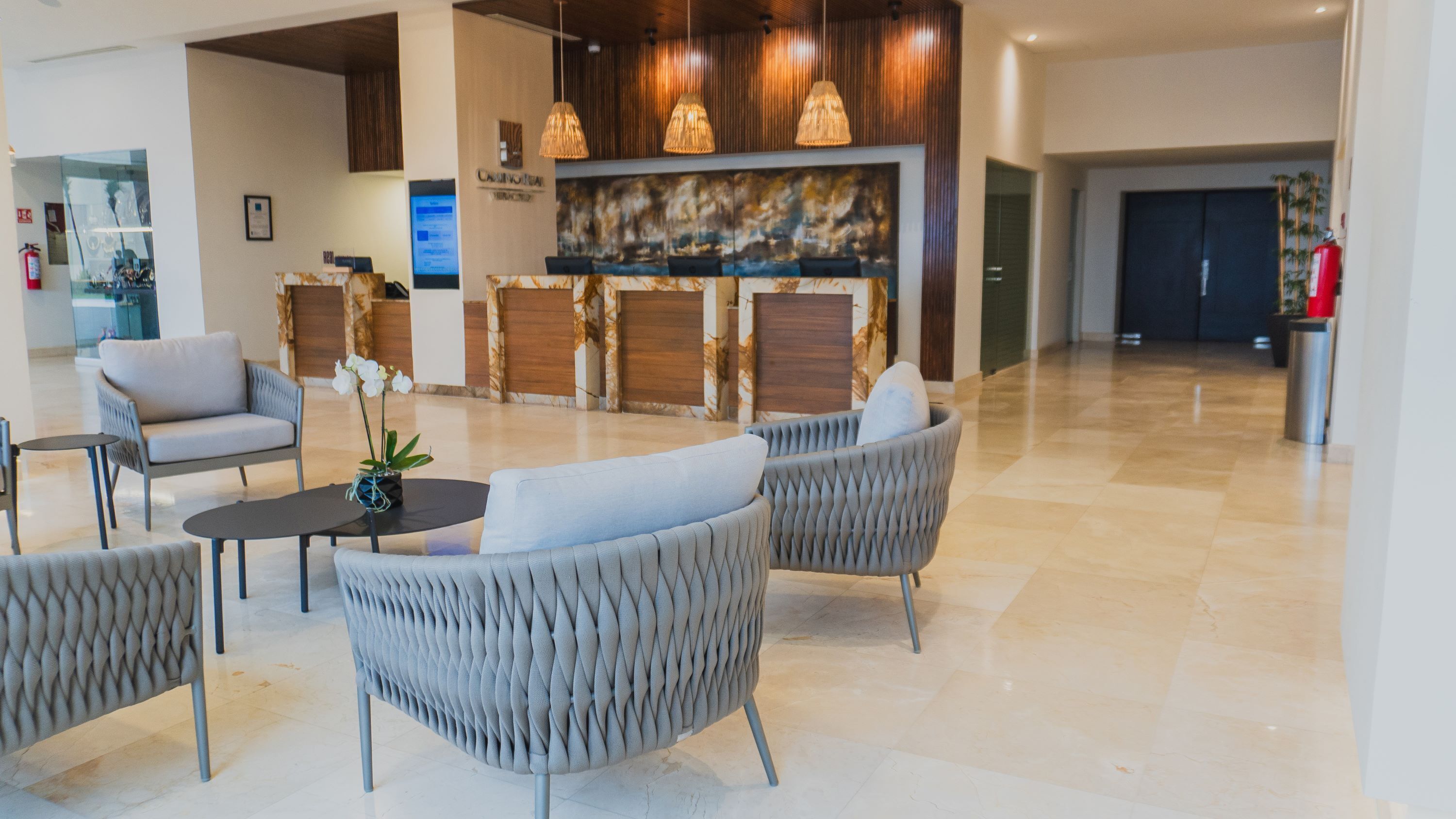 A lobby with modern furniture, a reception desk, and a large wall art piece.