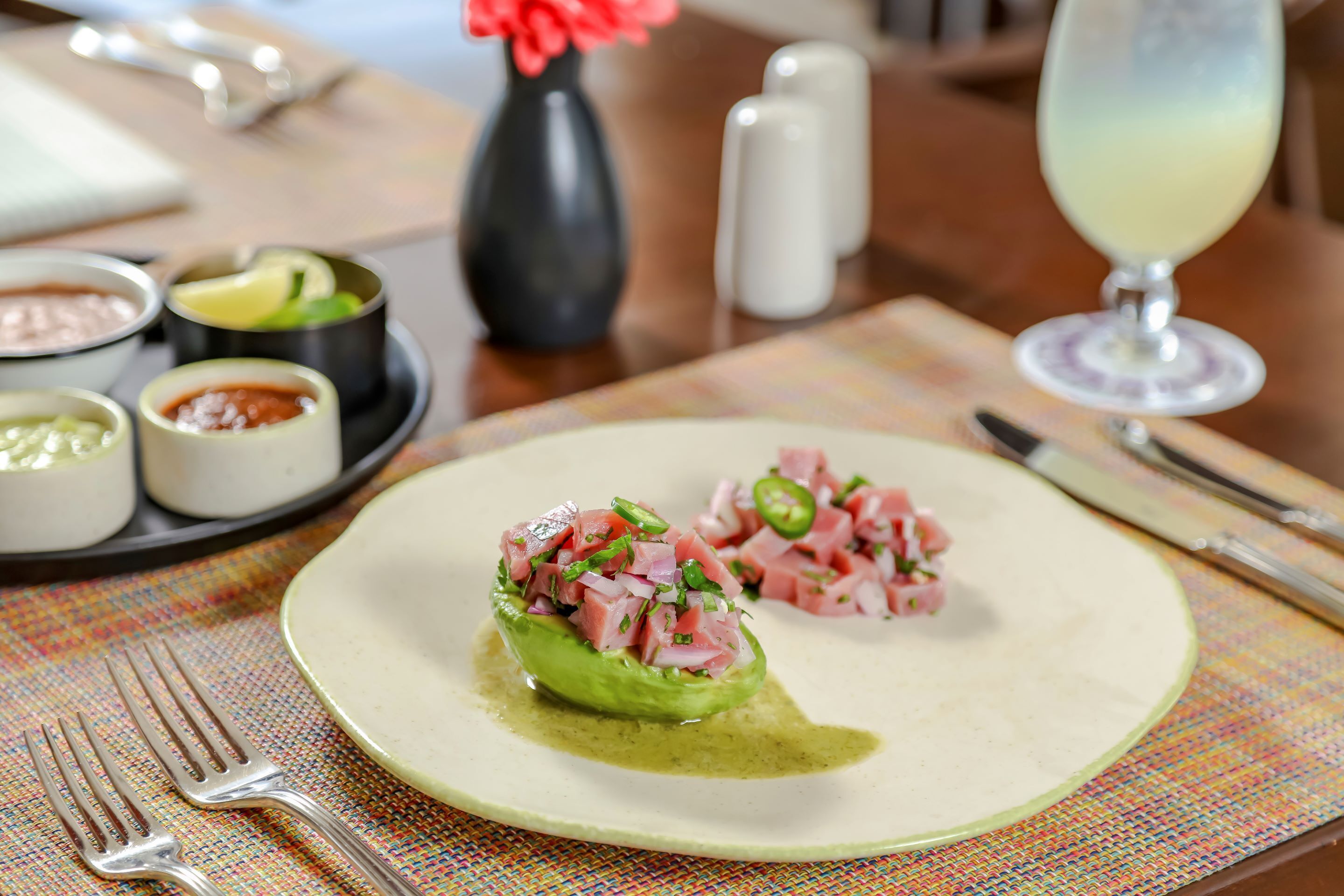 A plate with a dish of meat and avocado on a table with a placemat.