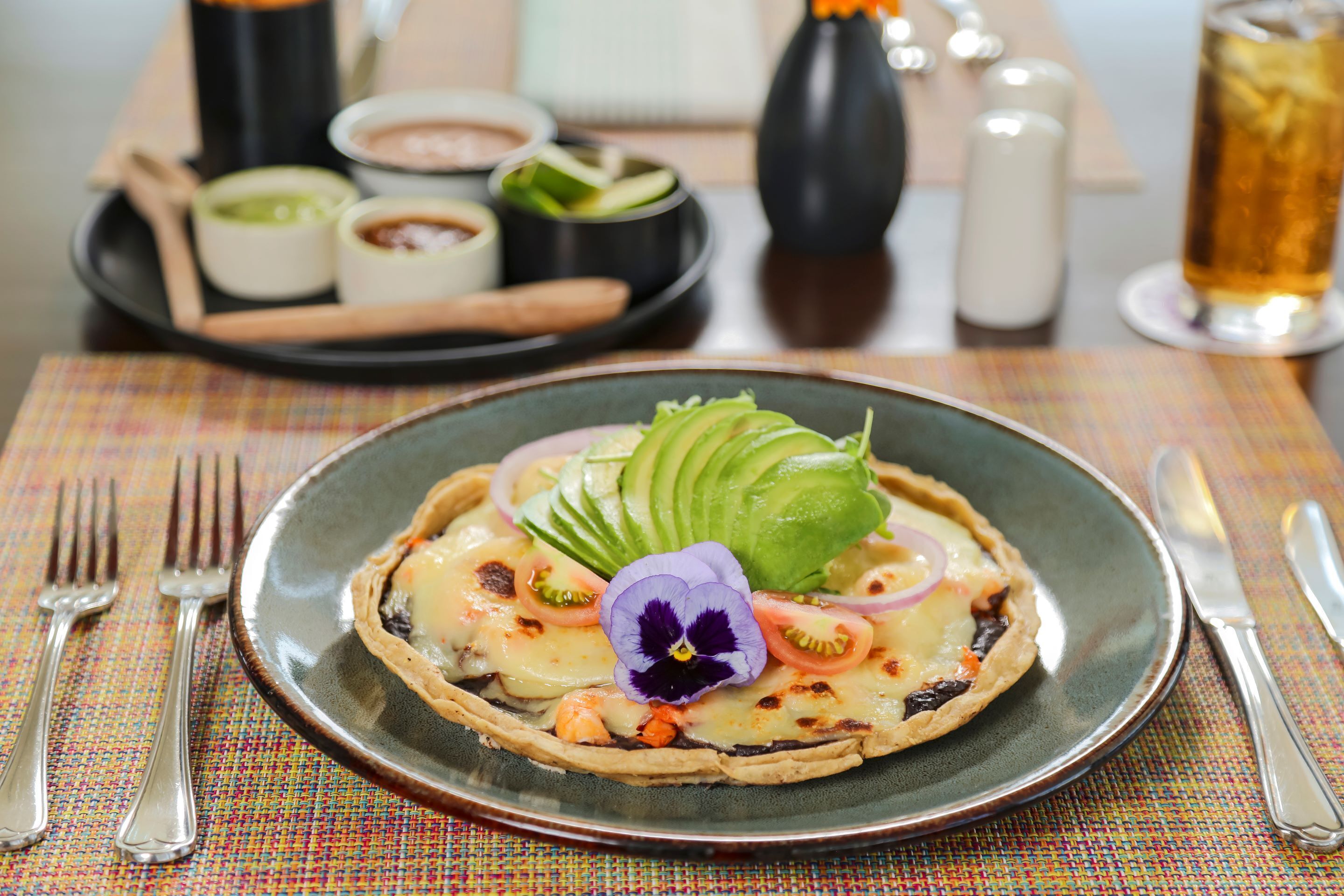 A plate of food with avocado, tomato, and a flower garnish.