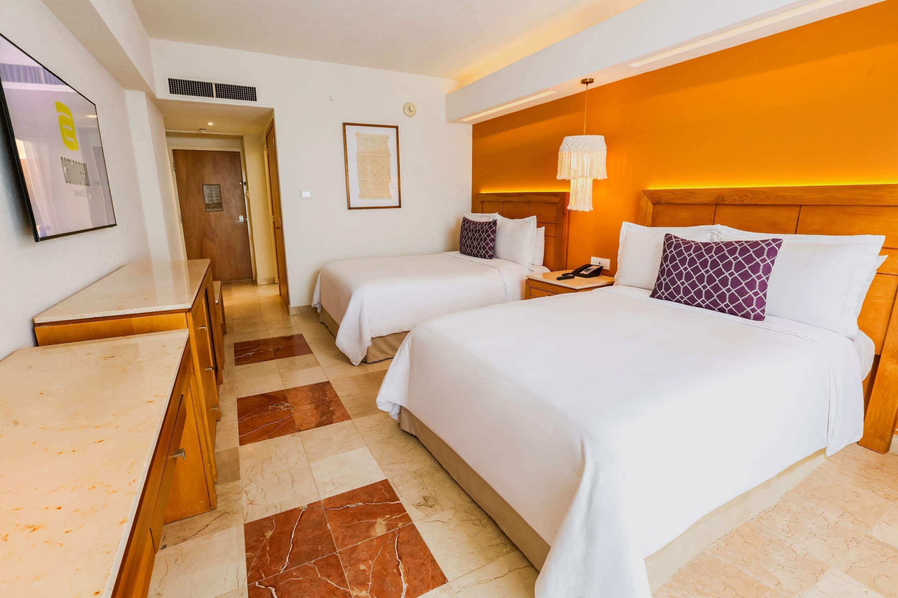 Habitació d'hotel amb dos llits, un escriptori i una porta al bany.