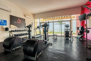 Ein Fitnessraum mit Laufbändern, Kurzhanteln und Trainingsgeräten, mit Blick auf eine schöne Aussicht.