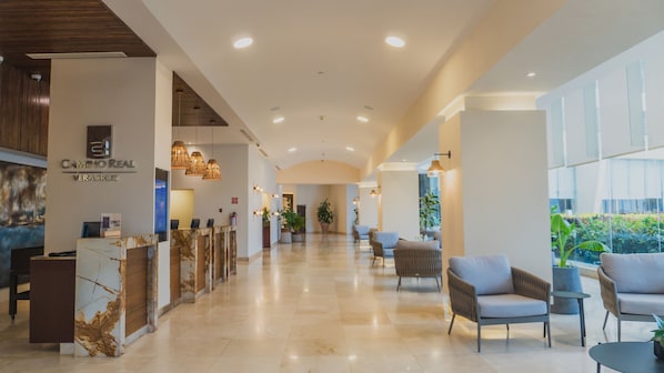 Eine Hotelhalle mit Empfangsschalter, Sitzgelegenheiten und großen Fenstern.