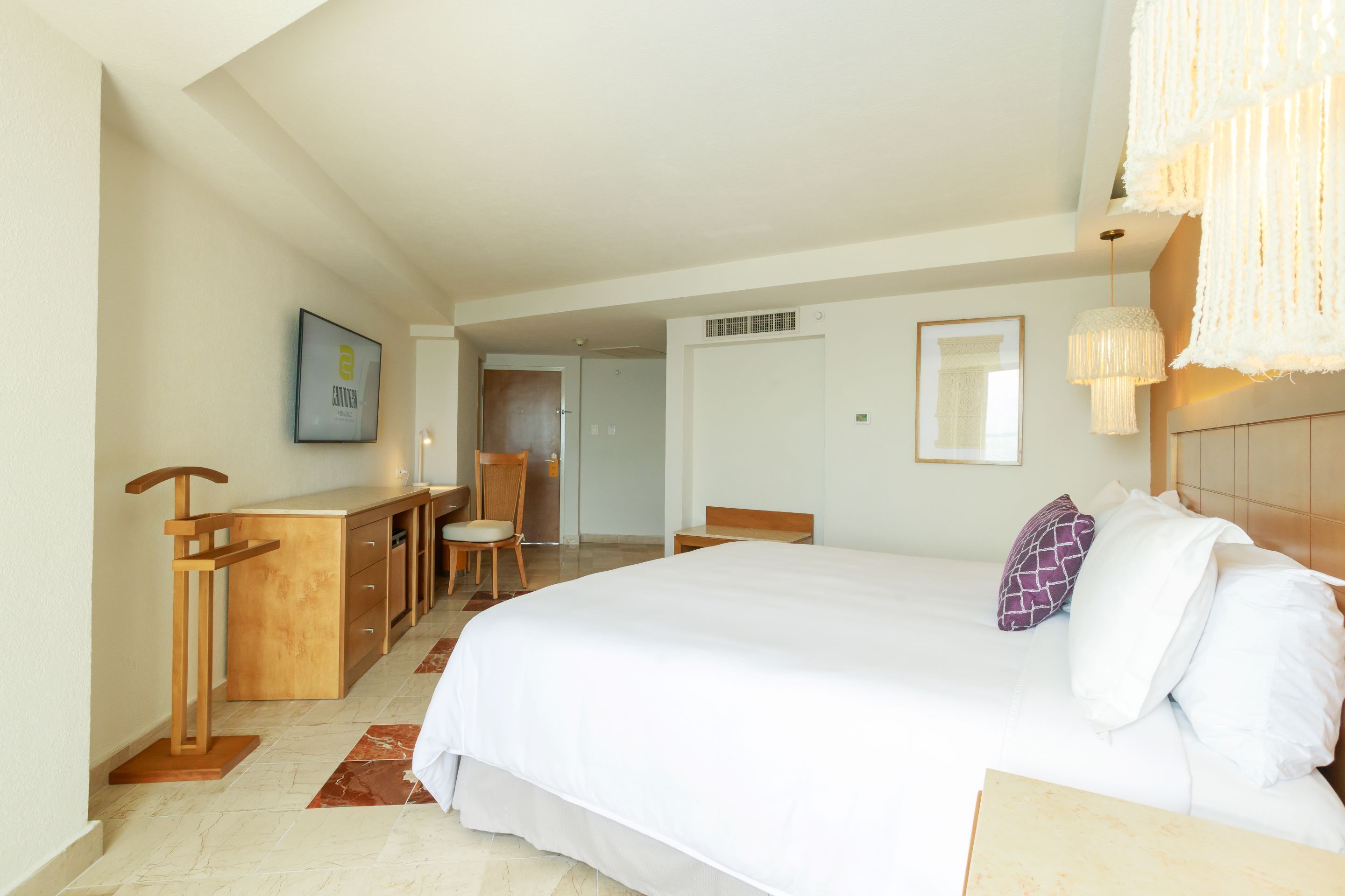 Habitación de hotel con una cama grande, un escritorio, una silla y una lámpara colgante.