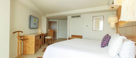 Habitación de hotel con una cama grande, un escritorio, una silla y una lámpara colgante.