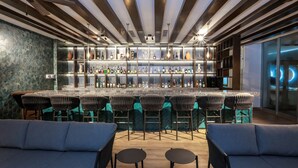 A modern bar area with a long counter, multiple bar stools, and a seating area with sofas and tables. - Camino Real Veracruz (Boca del Río)