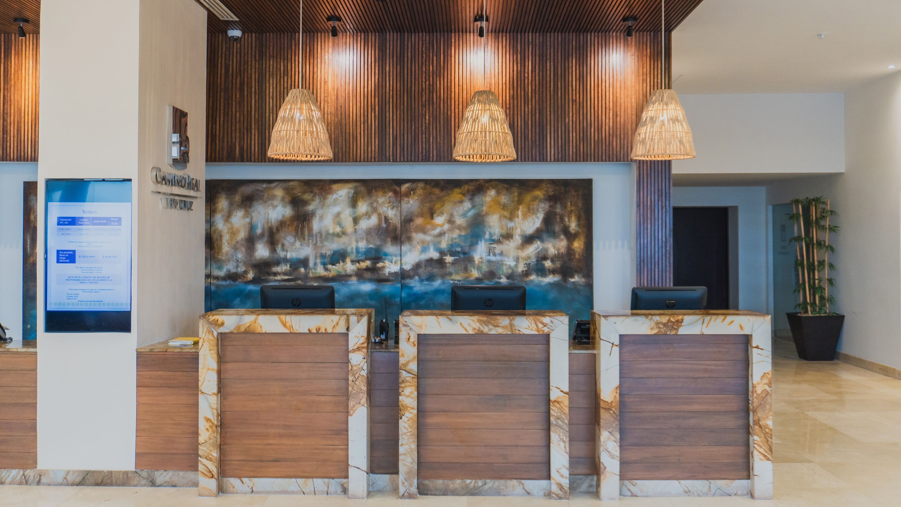 A reception area with a large abstract painting, wooden reception desk, and pendant lighting.