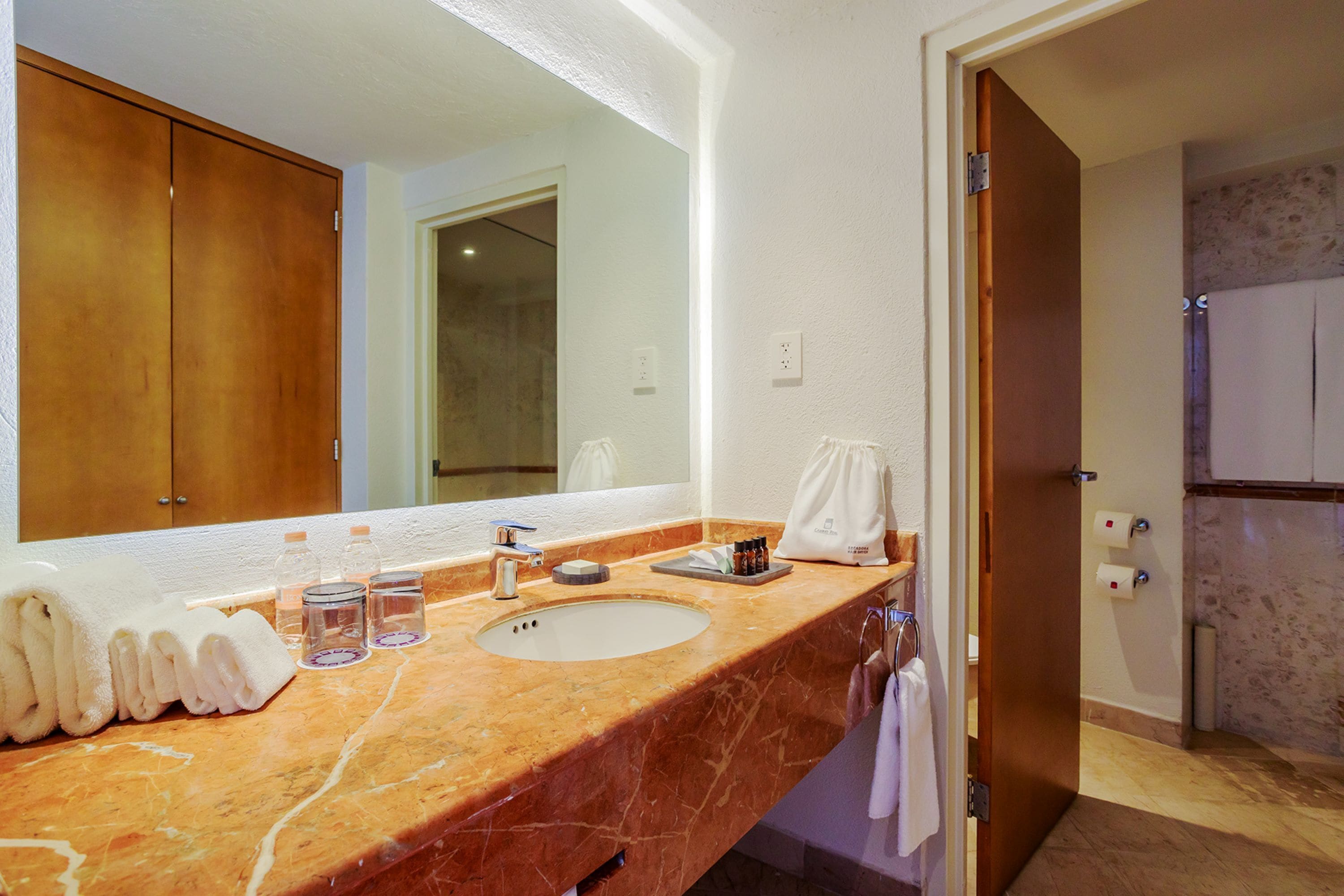 A bathroom with a marble sink, a large mirror, and a wooden door.