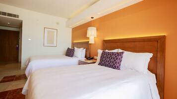 A hotel room with two beds, a wooden headboard, a nightstand, a framed picture on the wall, and a hanging light fixture.