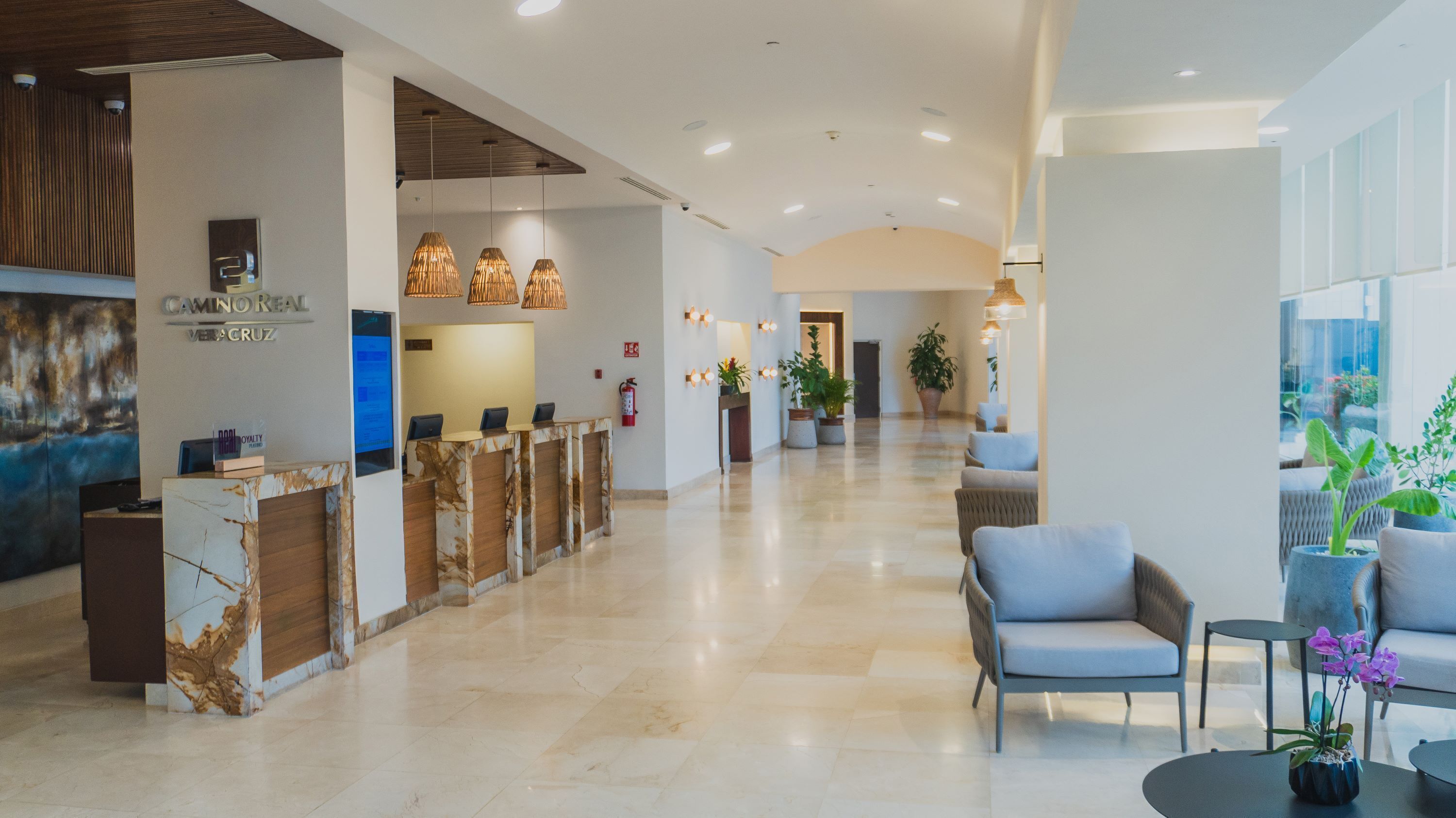 A hotel lobby with a reception desk, seating area, and a large window.