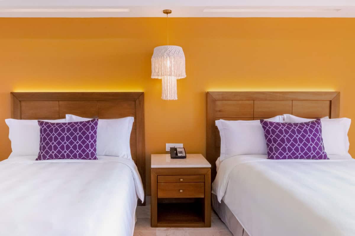 Ein Hotelzimmer mit zwei Betten, einem Nachttisch mit Telefon und einer Pendelleuchte.