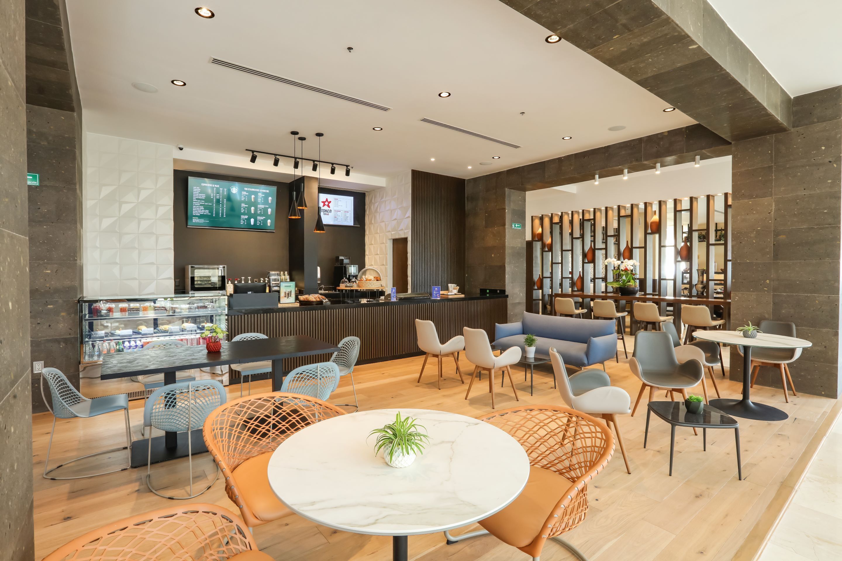 Een moderne hotel lobby met een receptiebalie, een zithoek en een koffiebar.