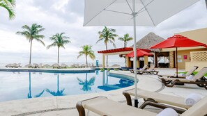 A poolside area with lounge chairs and umbrellas, palm trees, and a view of the ocean. - Camino Real Veracruz (Boca del Río)