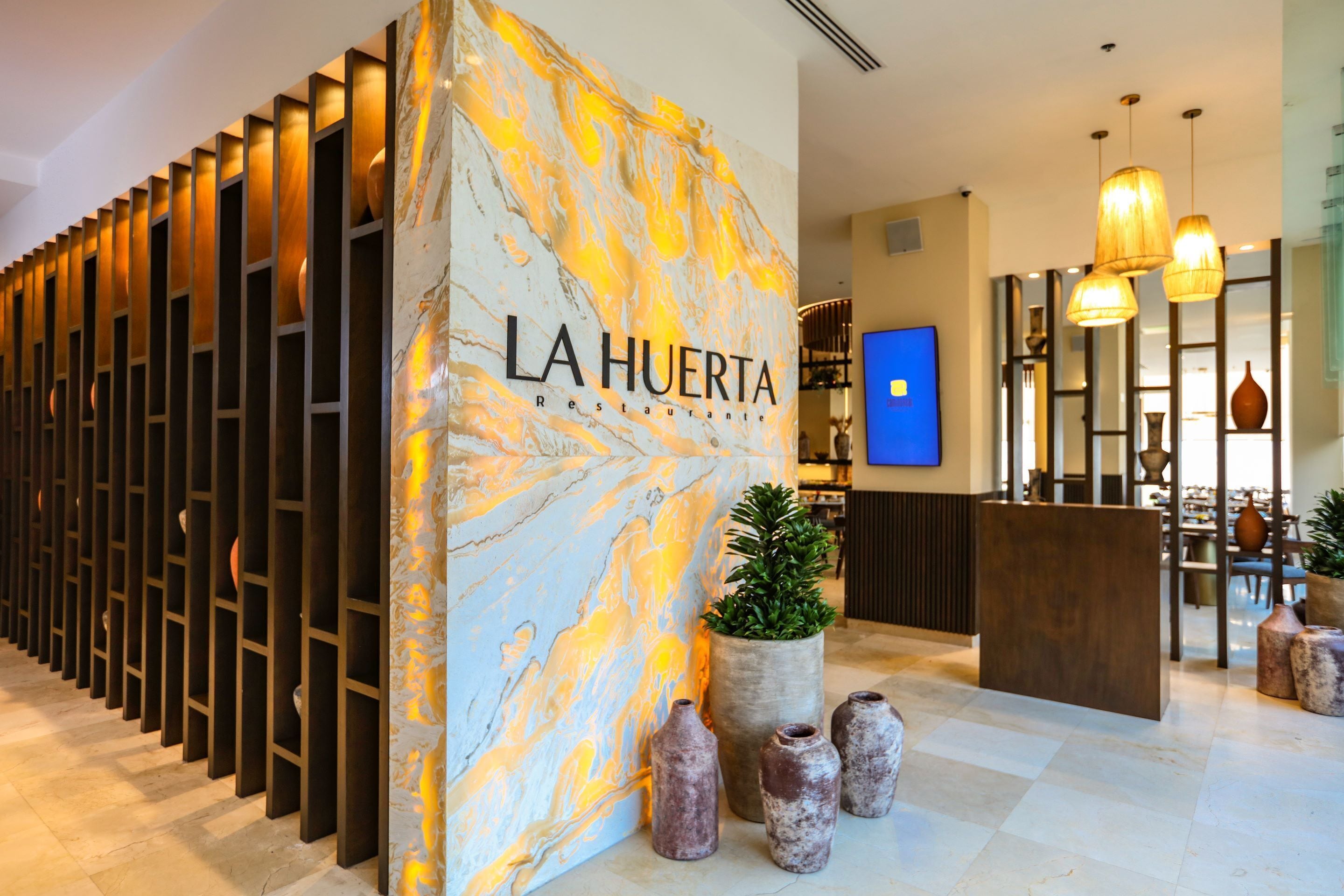 A reception area with a marble wall, a plant, and a wooden reception desk.