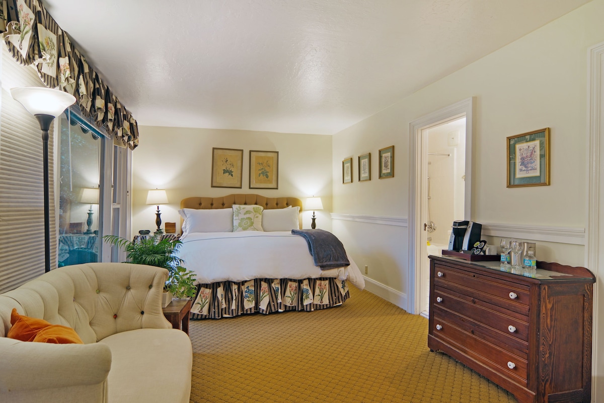 A bedroom with a bed, bedside lamps, a dresser, and a chair.