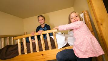 A bunk bed with two children sitting on it.