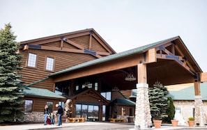 A log cabin-style building with a stone foundation, wooden beams, and a green roof. - Tundra Lodge (Green Bay)