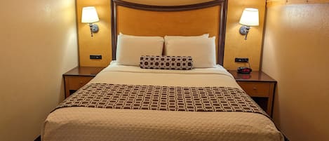 Ein Hotelzimmer mit einem großen Bett, zwei Nachttischen und Wandlampen.