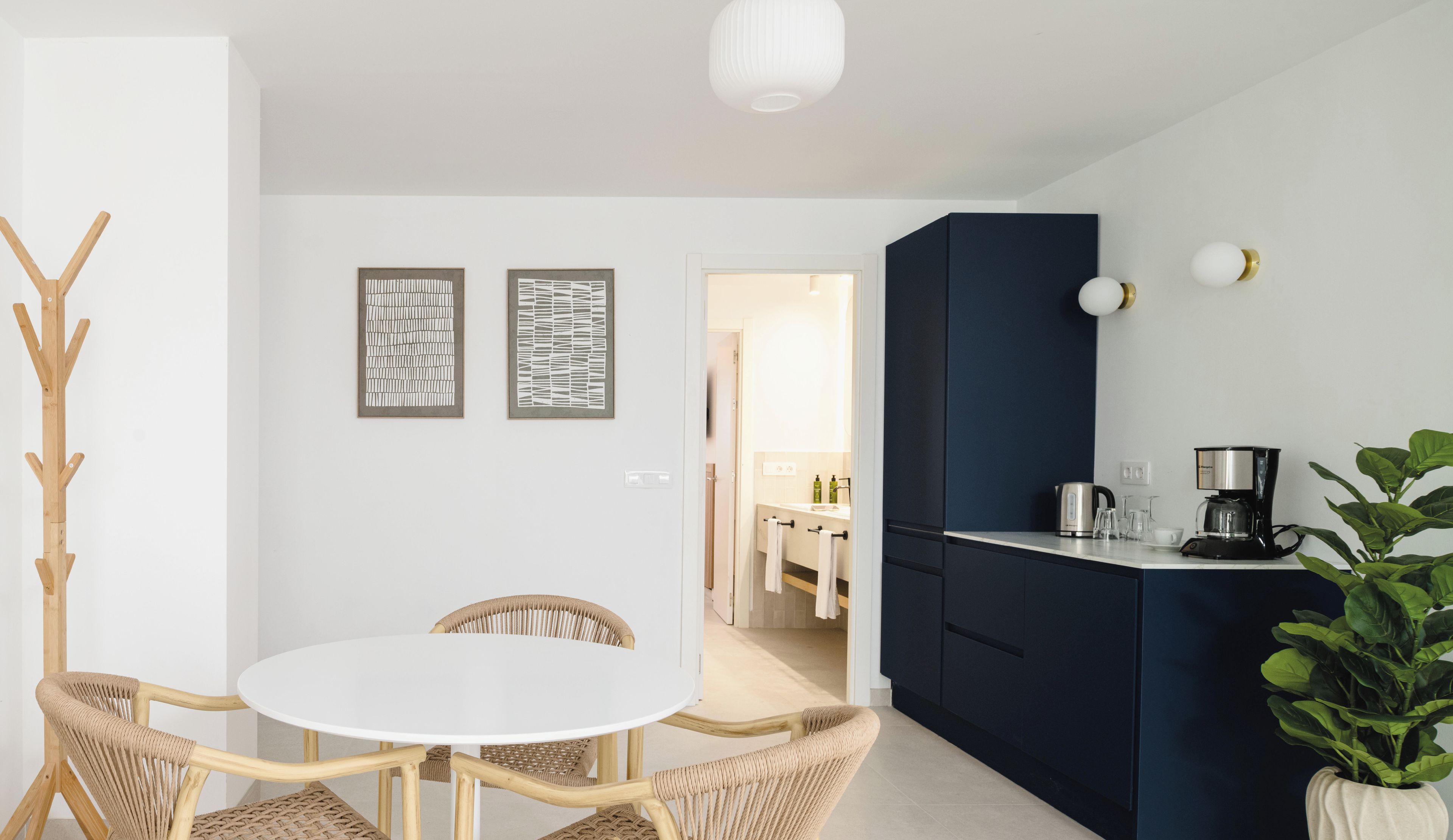 Una cocina moderna con un armario azul oscuro, una cafetera y una planta en maceta.