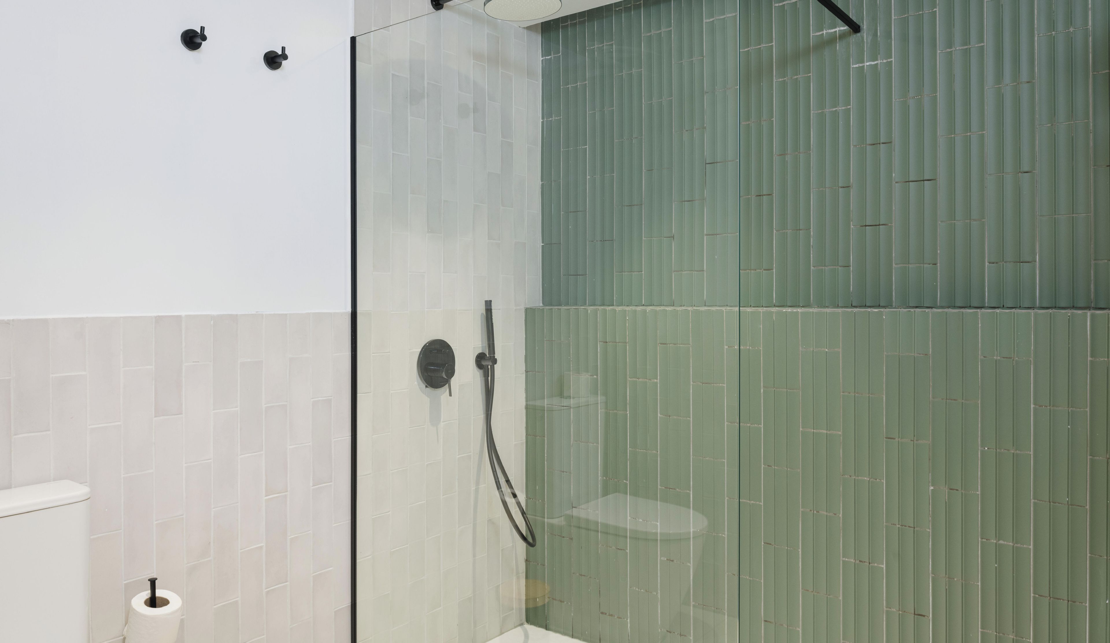 A bathroom with a glass shower enclosure, a toilet, and a towel rack.