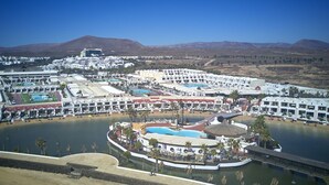 A resort with multiple swimming pools, a central water feature, and a bridge connecting different areas. - Sands Beach Resort (Teguise)