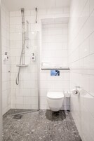 Un baño moderno con ducha, inodoro y perchero para toallas.