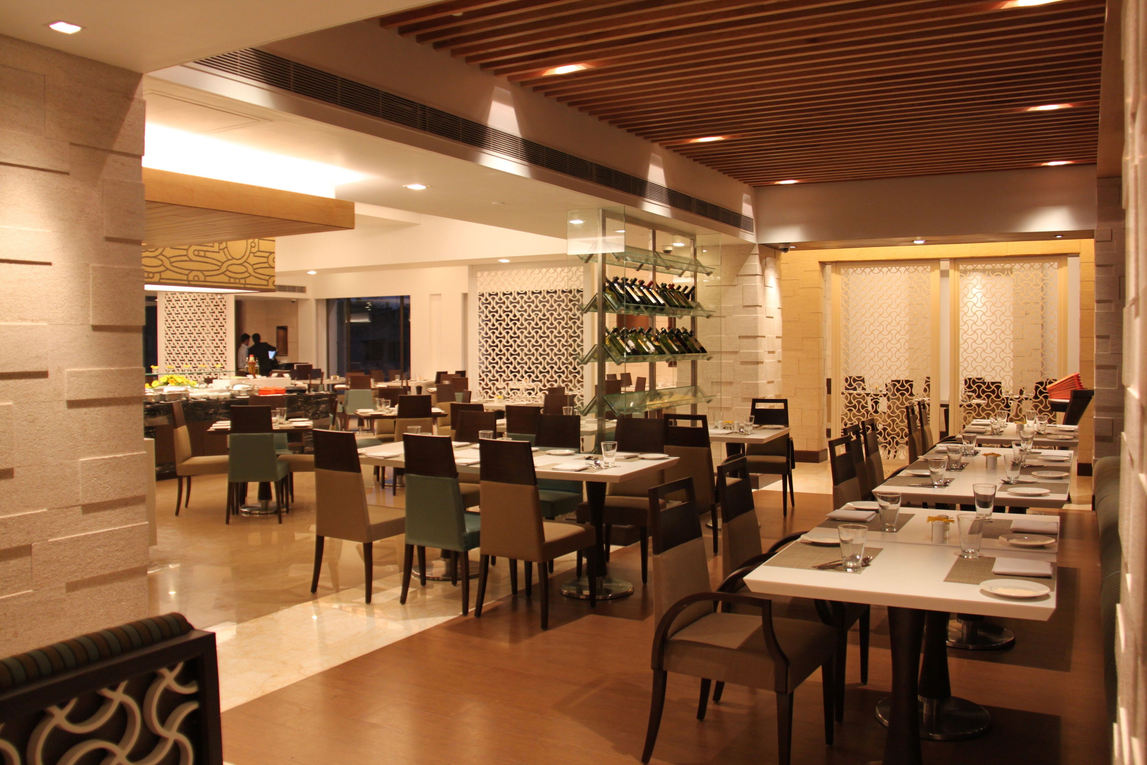A spacious restaurant with multiple dining tables and chairs, a wine rack, and a decorative wall pattern.
