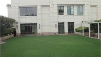 A two-story building with a flat roof, large windows, and a paved courtyard with a circular stone pattern.
