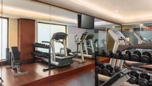 A gym with exercise equipment, including treadmills, dumbbells, and a bench. - Radisson Hotel Varanasi (Varanasi)