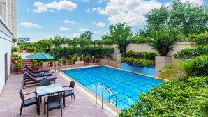 A swimming pool with a tiled deck, lounge chairs, and a table. - Radisson Hotel Varanasi (Varanasi)