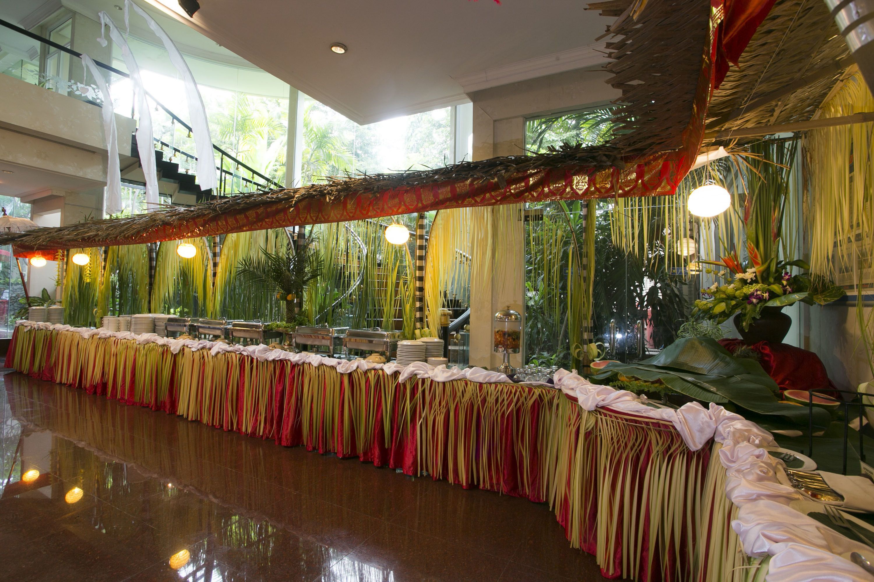 A banquet hall with a long table adorned with draped fabric and floral arrangements.