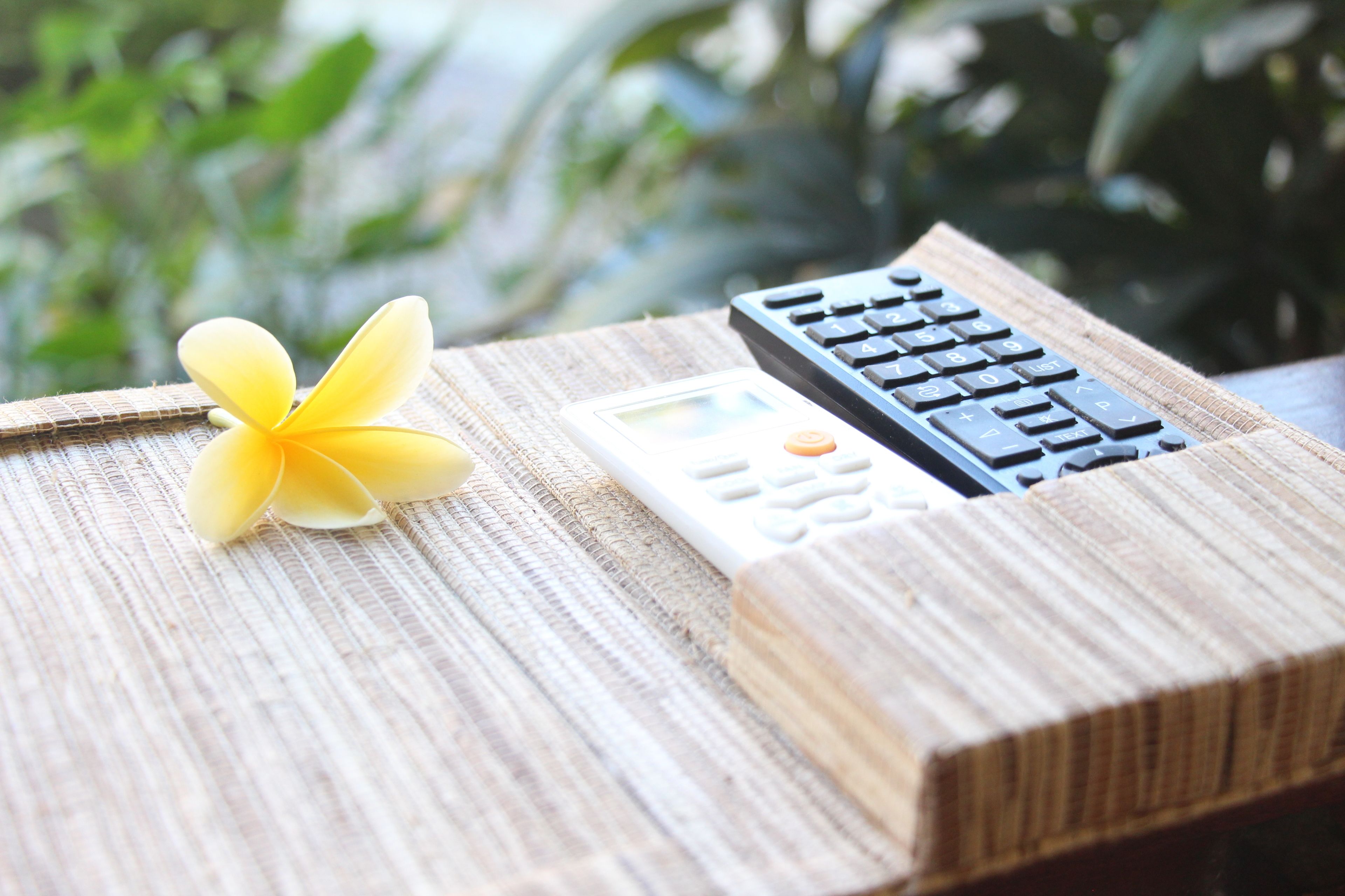 A wooden table with a calculator and a remote control on it.
