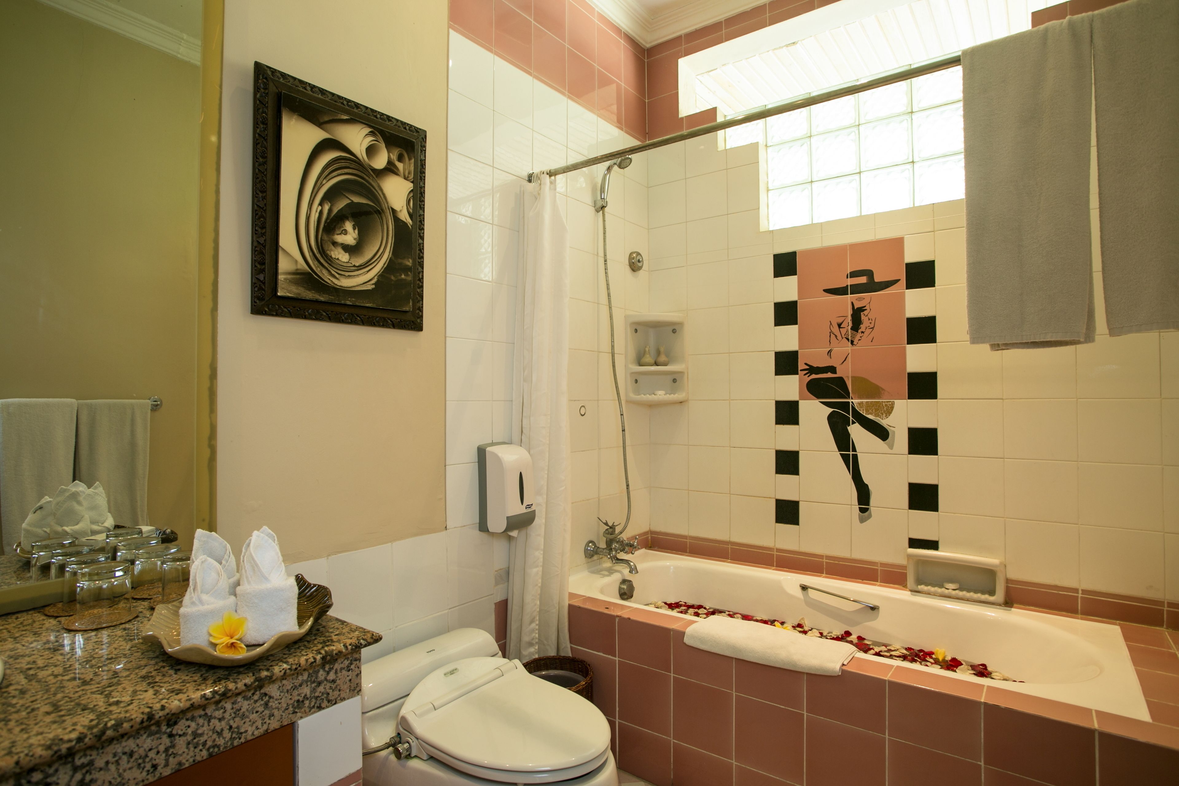 Un baño con bañera, inodoro y ducha. Hay toallas y artículos de aseo en la encimera.