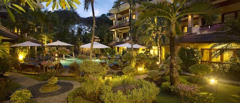 A resort with a swimming pool, outdoor seating, and lush landscaping.
